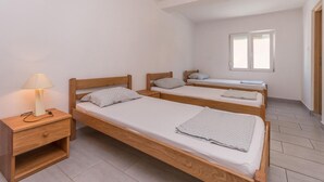 Une chambre de dortoir équipée de trois lits superposés en bois, d’une table de chevet avec une lampe et d’une fenêtre laissant entrer la lumière naturelle.