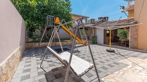 Un espace extérieur aménagé avec une balançoire, un coin salon abrité et une antenne parabolique.