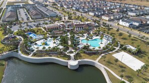 An aerial view of a residential area with a large swimming pool surrounded by palm trees and a bridge over a body of water. - 9BR house sleeps 22 with private pool and game (Kissimmee)