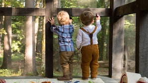 Two children standing by a window, looking outside.