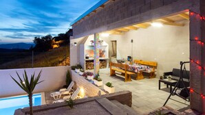 Un patio exterior moderno con piscina, sillas de descanso y zona de comedor con mesa y sillas.