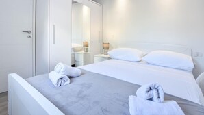 Una habitación de hotel moderna con una cama, dos mesitas de noche, un armario y un espejo.