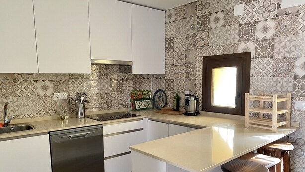 A modern kitchen with white cabinets, a dishwasher, a sink, and a wooden bar stool. - RURAL HOUSE TOLEDO/MADRID (Borox)