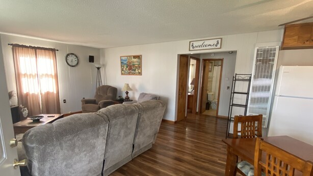 A living room with a sofa, a dining table with chairs, a clock, a lamp, and a 'welcome' sign. - Cozy house/attached garage close to Lucas Oil Race Track and Pomme De Terre Lake (Wheatland)