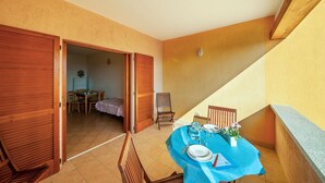 Un comedor con una mesa dispuesta para dos personas, una silla y una mesita con un jarrón de flores.
