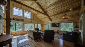 Ein geräumiges Wohnzimmer mit Holzböden, großen Fenstern und einer Chandelier.
