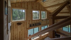 Eine Hütte mit zahlreichen Fenstern, die Blick auf einen Wald und einen See bietet.