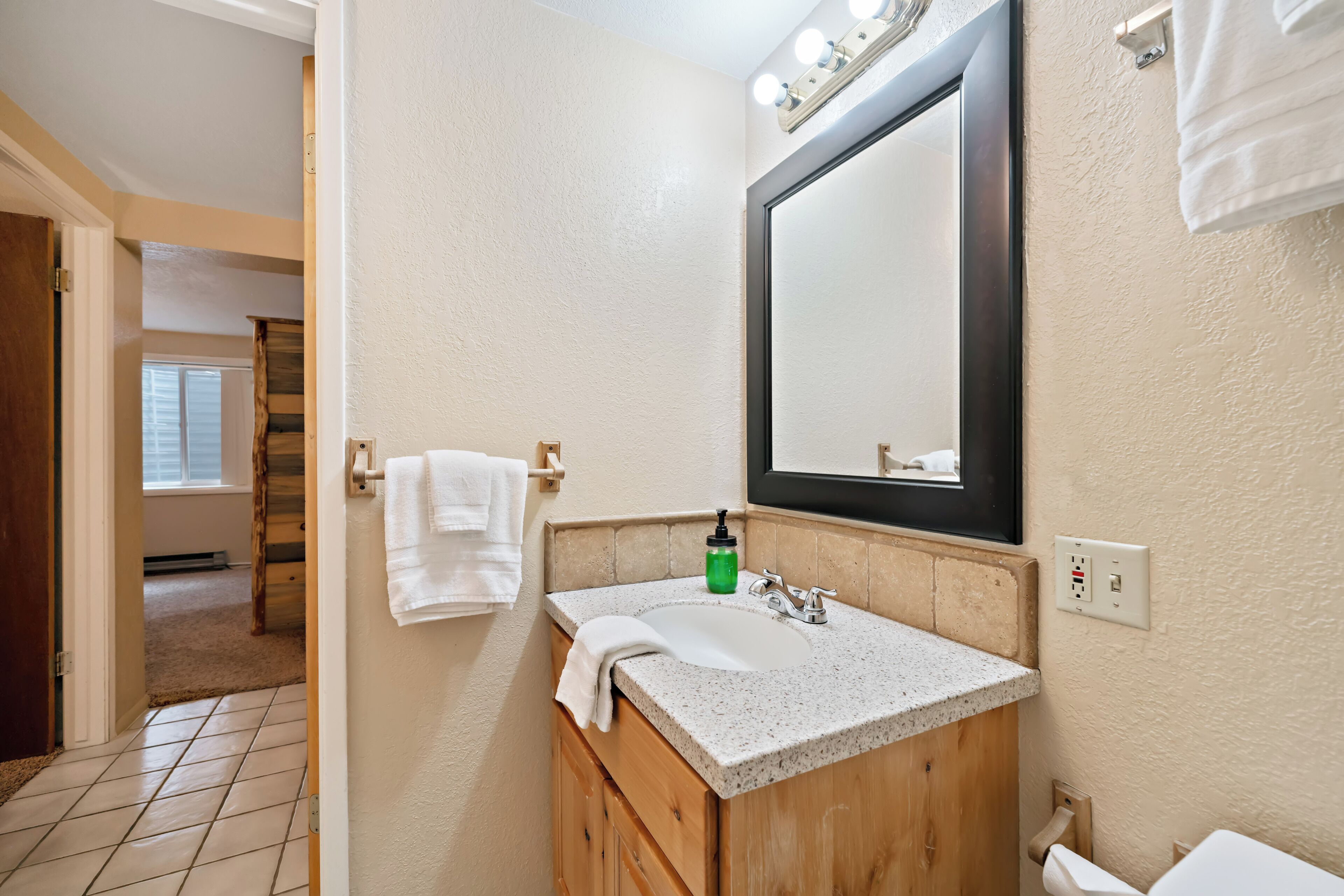 A bathroom with a sink, mirror, towel rack, and wooden vanity.