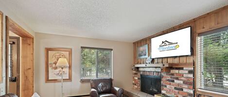 A living room with a leather couch, a wooden coffee table, a fireplace, and a mounted television.