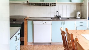 A kitchen with a stove, oven, sink, and a refrigerator. There is a wooden table and chairs.