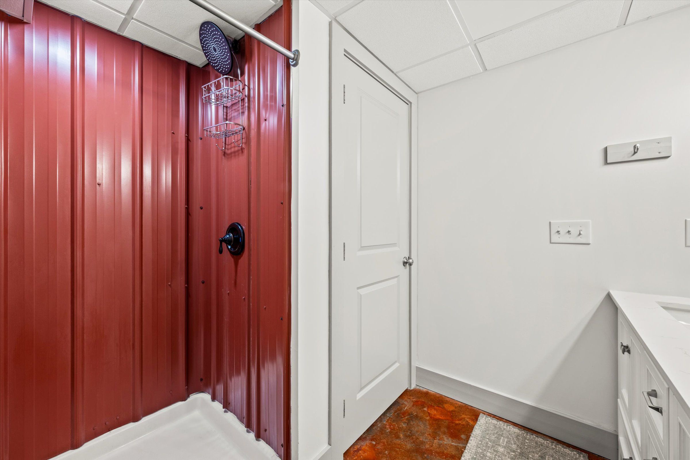 A room with a red wall, white door, and a white sink.