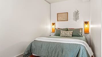 Un dormitorio con una cama, dos lámparas de pared, una obra de arte con hojas enmarcada y un cartel que dice 'mejor juntos'.