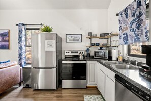 A modern kitchen with stainless steel appliances, a microwave, and a kettle on the stove. - Backwoods Bungalow (Horse Shoe)