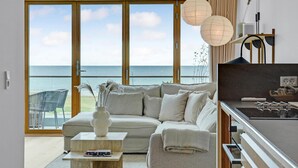 A modern living room with a sofa, coffee table, and a view of the sea. - Cozy apartment in Kerteminde with WiFi (Kerteminde)