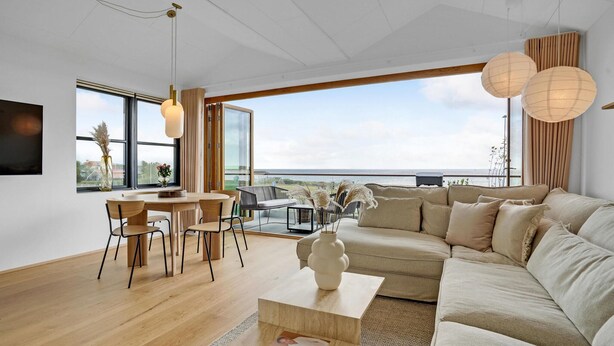A modern living room with a large sofa, a dining area with a table and chairs, and a view of the sea through large windows. - Cozy apartment in Kerteminde with WiFi (Kerteminde)