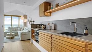 A modern kitchen with wooden cabinets, a black sink, and a view of the sea. - Cozy apartment in Kerteminde with WiFi (Kerteminde)