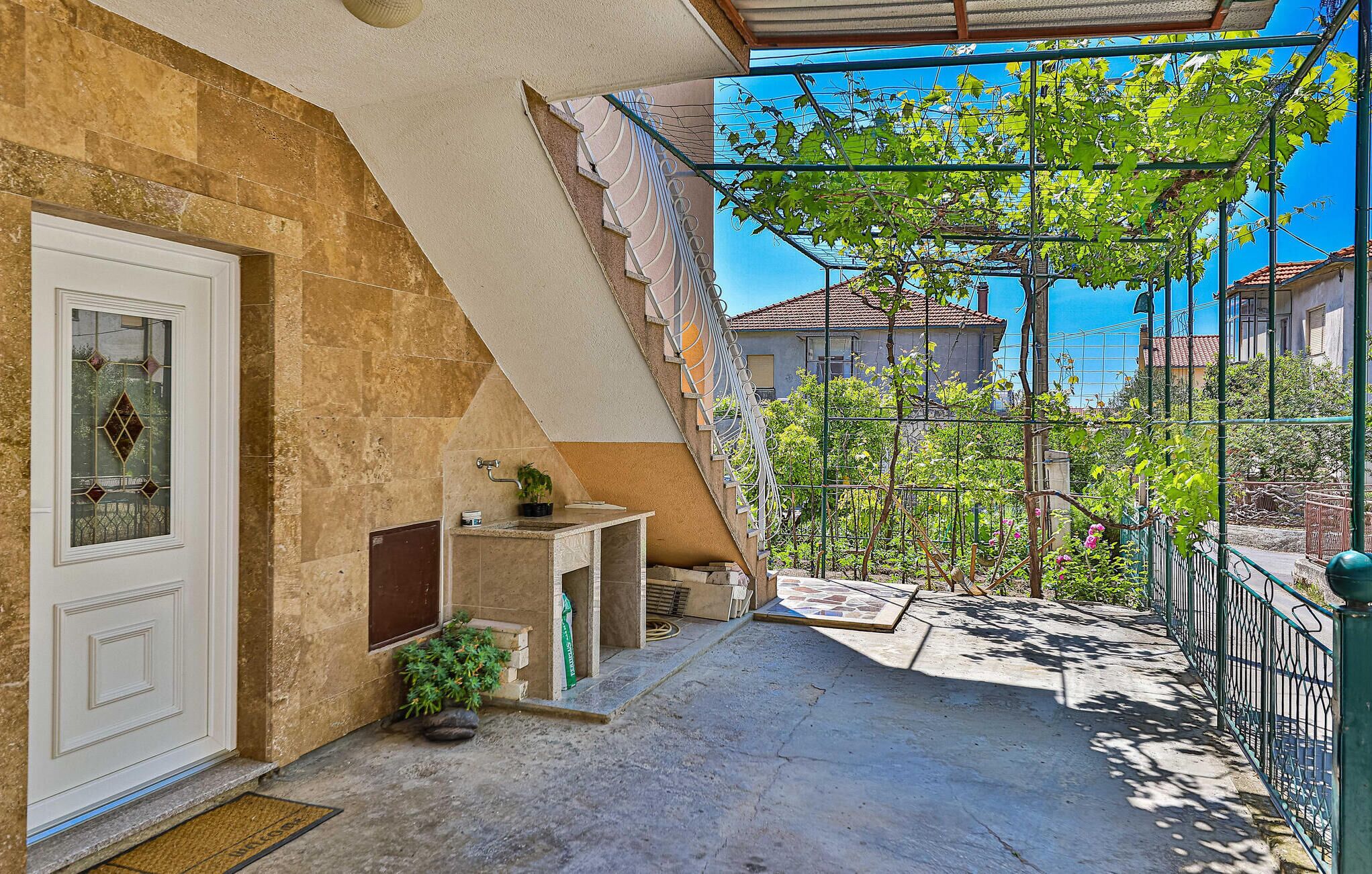 A balcony with a stone wall, a door, and a small plant.