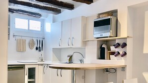 Une cuisine moderne avec des armoires blanches, un four à micro-ondes encastré et un coin bar avec deux chaises blanches.