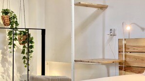 Une chambre à coucher moderne avec un lit, une plante suspendue, une étagère en bois et une table de chevet.