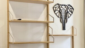 Un coin de pièce avec une étagère en bois et une sculpture décorative représentant la tête d’un éléphant.