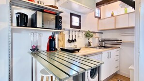 Une cuisine compacte équipée d’un lave-linge intégré, d’une machine à café et d’un four à micro-ondes.