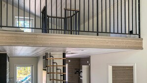 Un interior de varios niveles con una escalera de madera y barandas de metal.