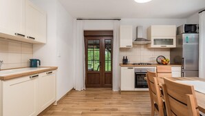 Eine moderne Küche mit weißen Schränken, einer Holzauskładung, einer Mikrowelle, einem Kühlschrank und einem Essbereich mit einem Holztisch und Stühlen.