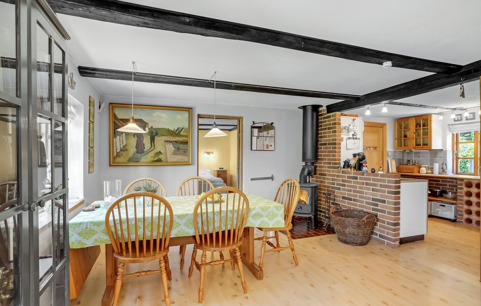 Un coin repas avec une table dressée pour quatre personnes, des chaises en bois et un tableau accroché au mur.