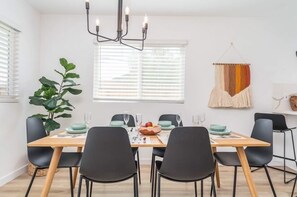 A dining area with a wooden table, black chairs, and a chandelier.