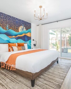 A bedroom with a large bed, a mural on the wall, a chandelier, and a view of the outdoors.