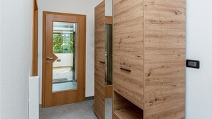 A modern interior with a wooden door leading to a balcony, a sliding wooden door, and a light switch on the wall.