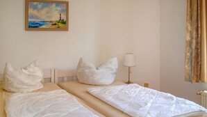 A hotel room with two beds, white bedding, a painting of a lighthouse, and a lamp. - 1 bedroom beautiful apartment in Wismar (Wismar)