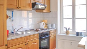 A kitchen with wooden cabinets, a stainless steel sink, a coffee maker, and a window with a view. - 1 bedroom beautiful apartment in Wismar (Wismar)