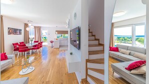 Un appartamento moderno con zona pranzo, cucina, soggiorno e una scala che conduce a un piano superiore.
