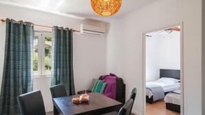 A room with a wooden table, chairs, a bed with a grey headboard, and a window with curtains. - 2 bedroom awesome apartment in Sutivan (Sutivan)