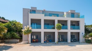 A modern multi-story building with balconies, outdoor seating, and a gravel driveway. - 2 bedroom awesome apartment in Sutivan (Sutivan)