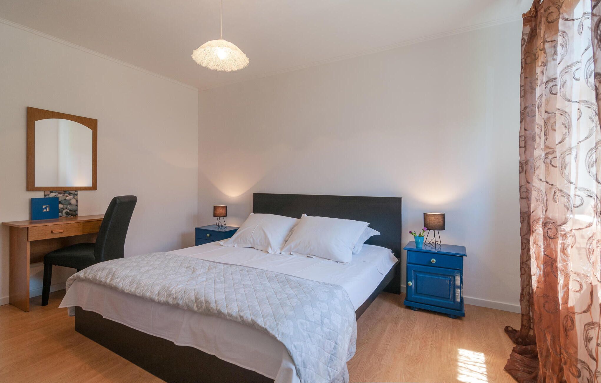 Une chambre bien rangée, avec un lit, un bureau et une chaise.