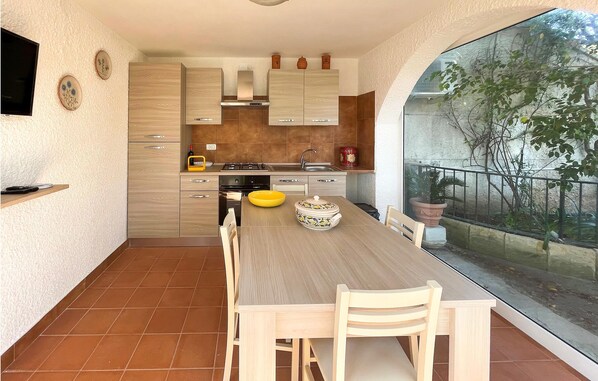 A modern kitchen with a dining table, chairs, and a large window overlooking a garden. - 2 bedroom lovely apartment in Frigole (Frigole)