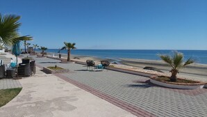 A paved walkway with outdoor seating and palm trees, leading to a beach. - Villa 8 A Great Place to Relax and Create Great Memories! (Puerto Peñasco)