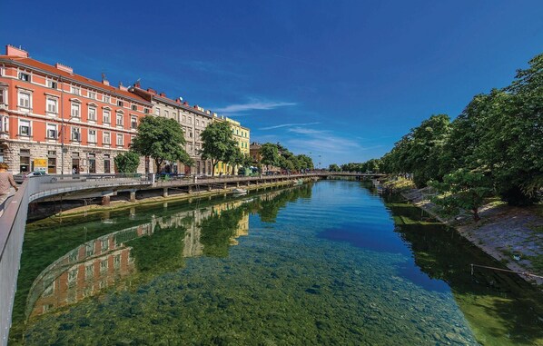 A clear river with buildings on one side and trees on the other. - Nice apartment in Rijeka with house sea view (Rijeka)