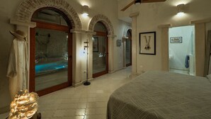 A bedroom with a large bed, a ceiling fan, and a view of a spa area. - Luxury Casa Lourdes in Merida, Centro (Mérida)