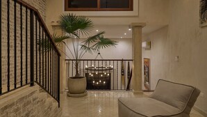 A spacious living area with a staircase, a large potted plant, a modern chandelier, and a comfortable sofa. - Luxury Casa Lourdes in Merida, Centro (Mérida)