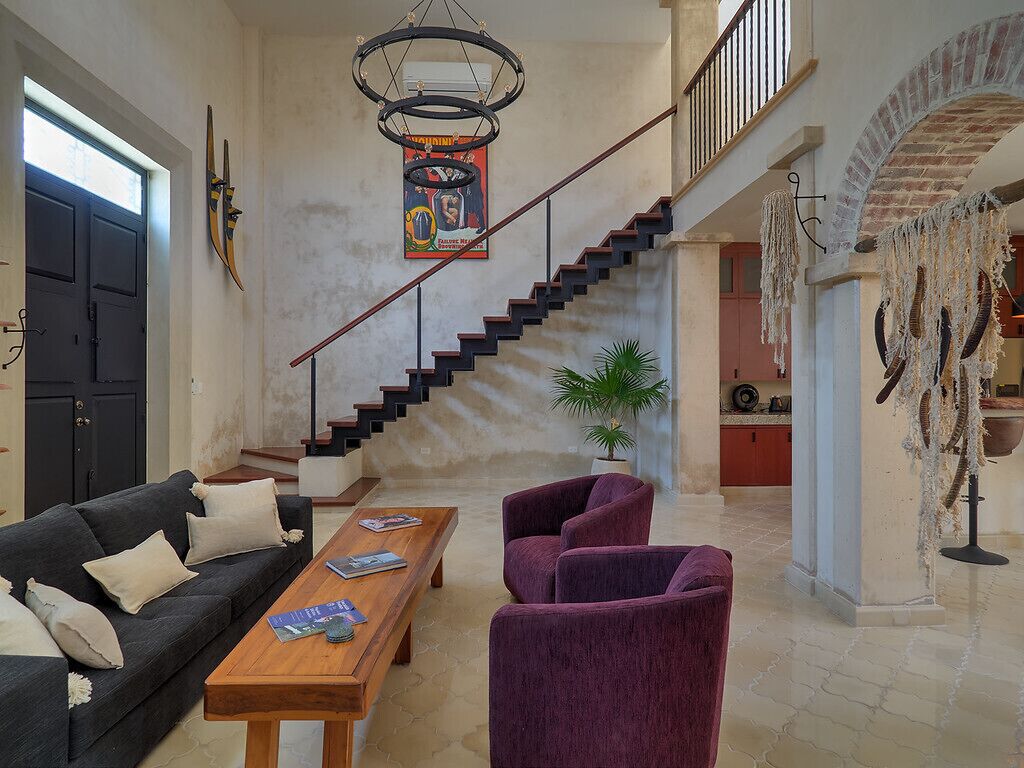 A spacious living area with a staircase, a sofa, a coffee table, and a potted plant.