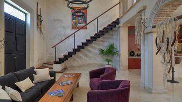 A spacious living area with a staircase, a sofa, a coffee table, and a potted plant.