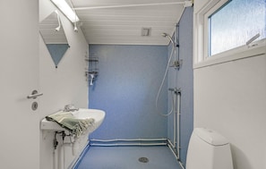 A compact bathroom with a shower, a sink, and a window.