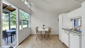A kitchen with a white interior, a dining table with chairs, and a view of the outdoors through large windows. - Amazing home in Hampen with WiFi (Hampen)