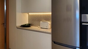 Una cocina con gabinetes blancos, encimera de granito, un tostador y un bol verde.