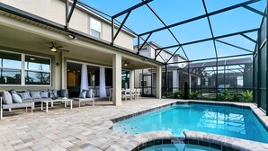 A modern outdoor pool area with a hot tub, seating, and a covered patio. - 9BR house with game room near Disney area (Kissimmee)