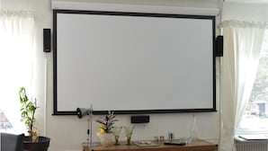 A room with a large projection screen, a potted plant, a lamp, and a small table with various items. - 4 bedroom nice home in Trosa (Trosa)
