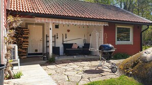 A house with a tiled roof, a covered porch with outdoor furniture, and a barbecue grill. - 4 bedroom nice home in Trosa (Trosa)